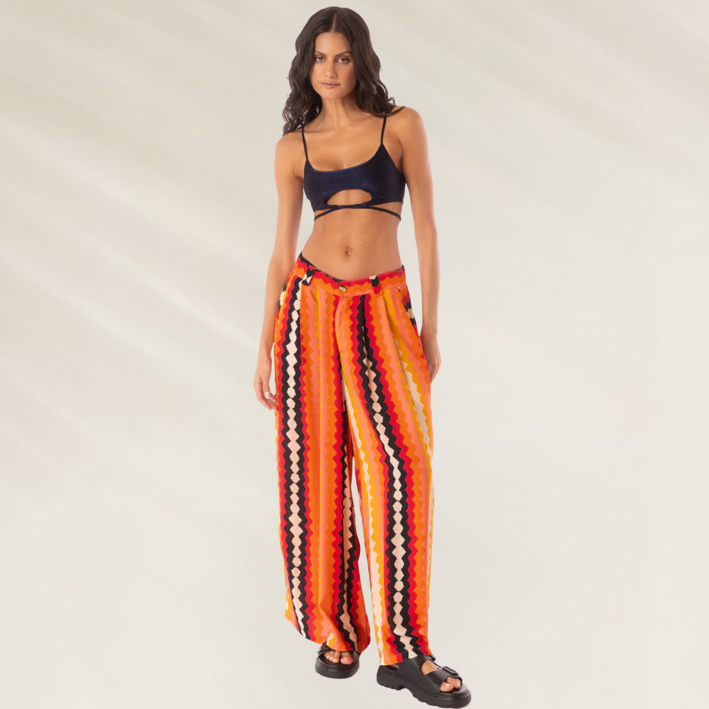 Modelo usando Calças Maaji Sabine Hyperflares listradas em tons laranja e vermelho, corte largo e cós com cordão