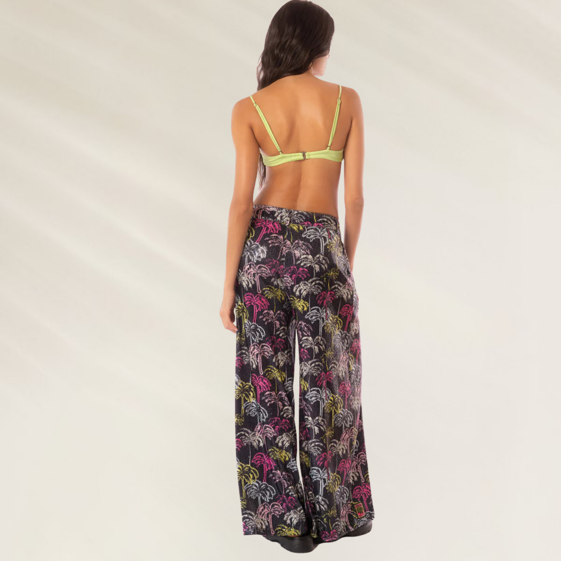 Calças Largas Stella Maaji com estampa colorida em fundo preto, modelo feminino visto de costas