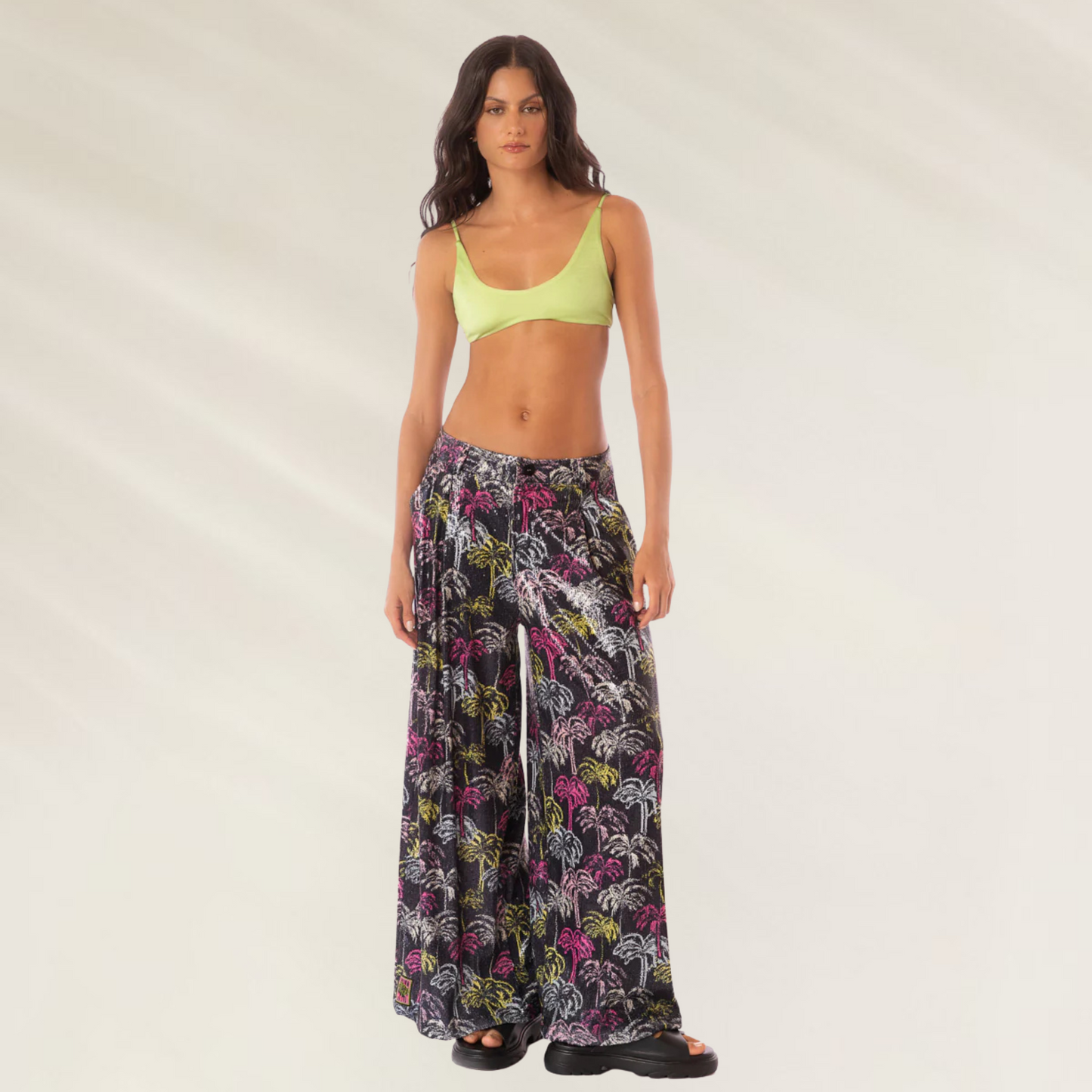 Calças Largas Stella Maaji estampadas com fundo preto usadas por mulher com top verde