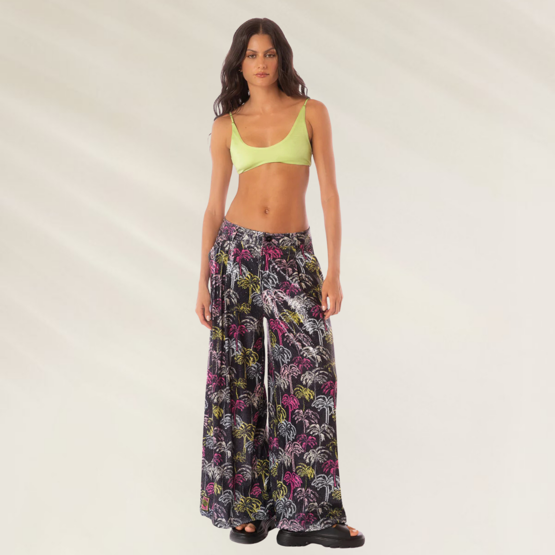 Calças Largas Stella Maaji estampadas com fundo preto usadas por mulher com top verde