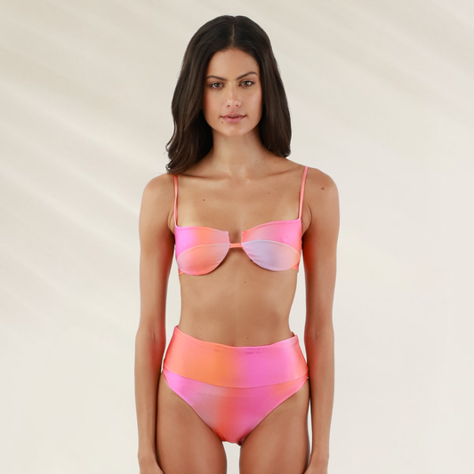 Modelo usando cueca Malai cintura subida com cobertura media em tons de rosa e laranja para conforto e estilo na praia