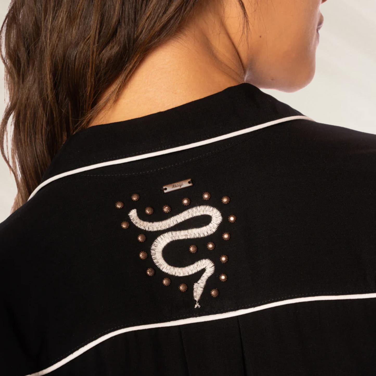 Detalhe da Camisa Longa Juicy Midnight Shadow da Maaji com bordado de cobra e acabamento branco