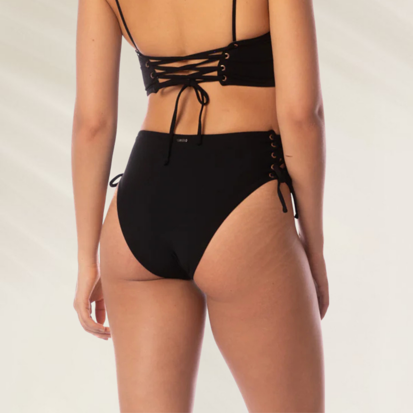 Vista traseira da Cueca Reversível Oasis Maaji preta com amarração lateral em modelo feminino