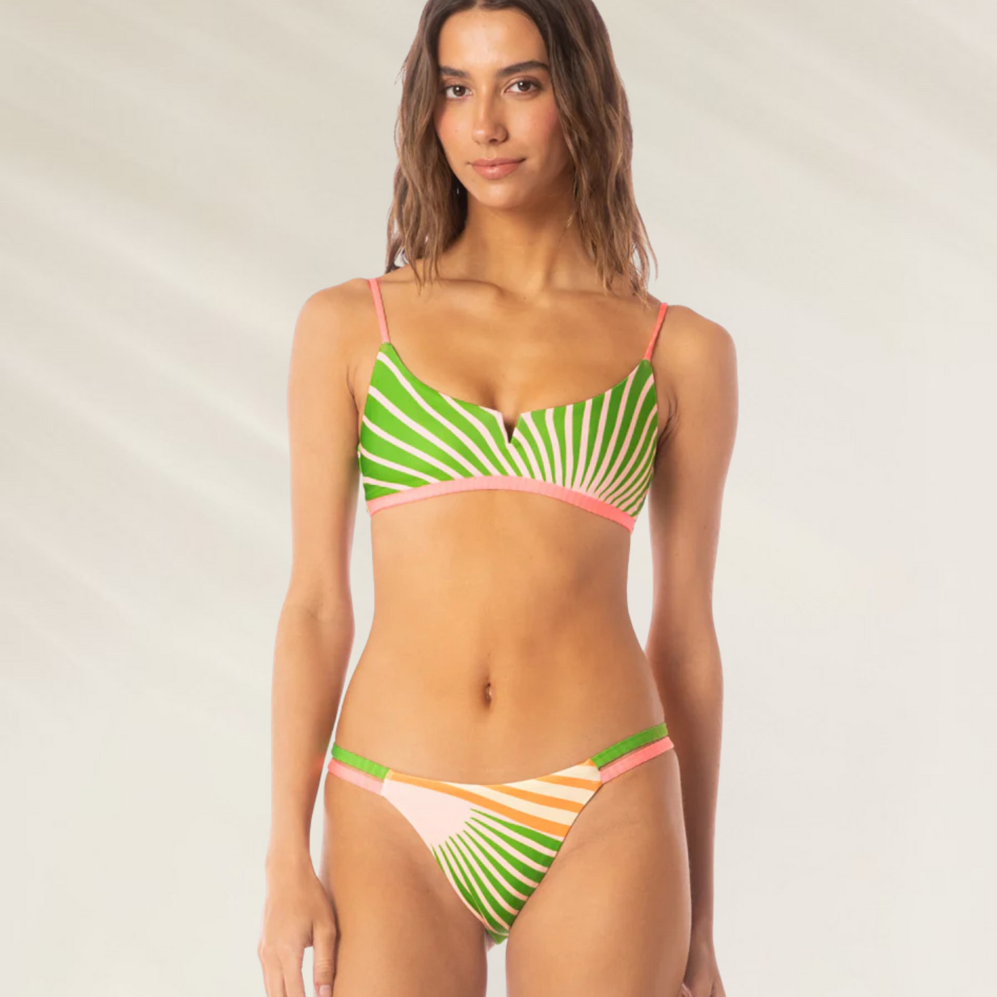 Mulher usando cueca de biquini Cueca Reversível Stellar Sunrise Colada Maaji com estampa listrada verde, rosa e laranja