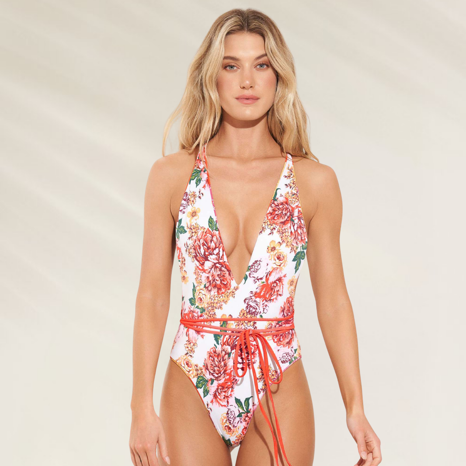 Mulher usando fato de banho reversível com alças convertíveis Maaji branco com estampa floral e cinto vermelho