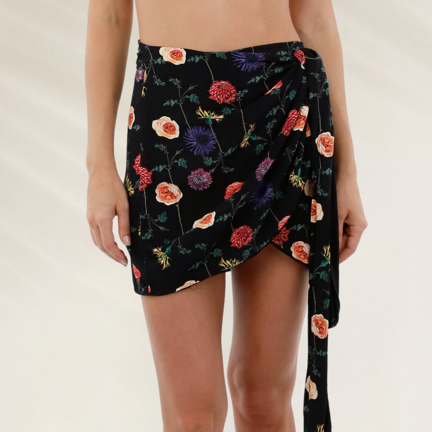 Saia Curta em Viscose com Estampado Floral Malai em fundo preto com flores coloridas e detalhe de amarração