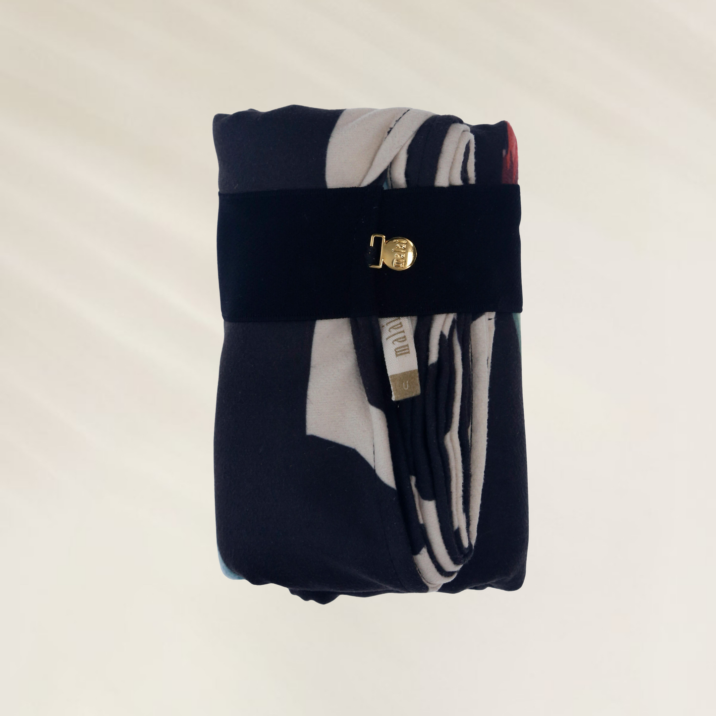 Toalha de Praia Malai – Leveza, Estilo e Praticidade dobrada com suporte preto e detalhe dourado