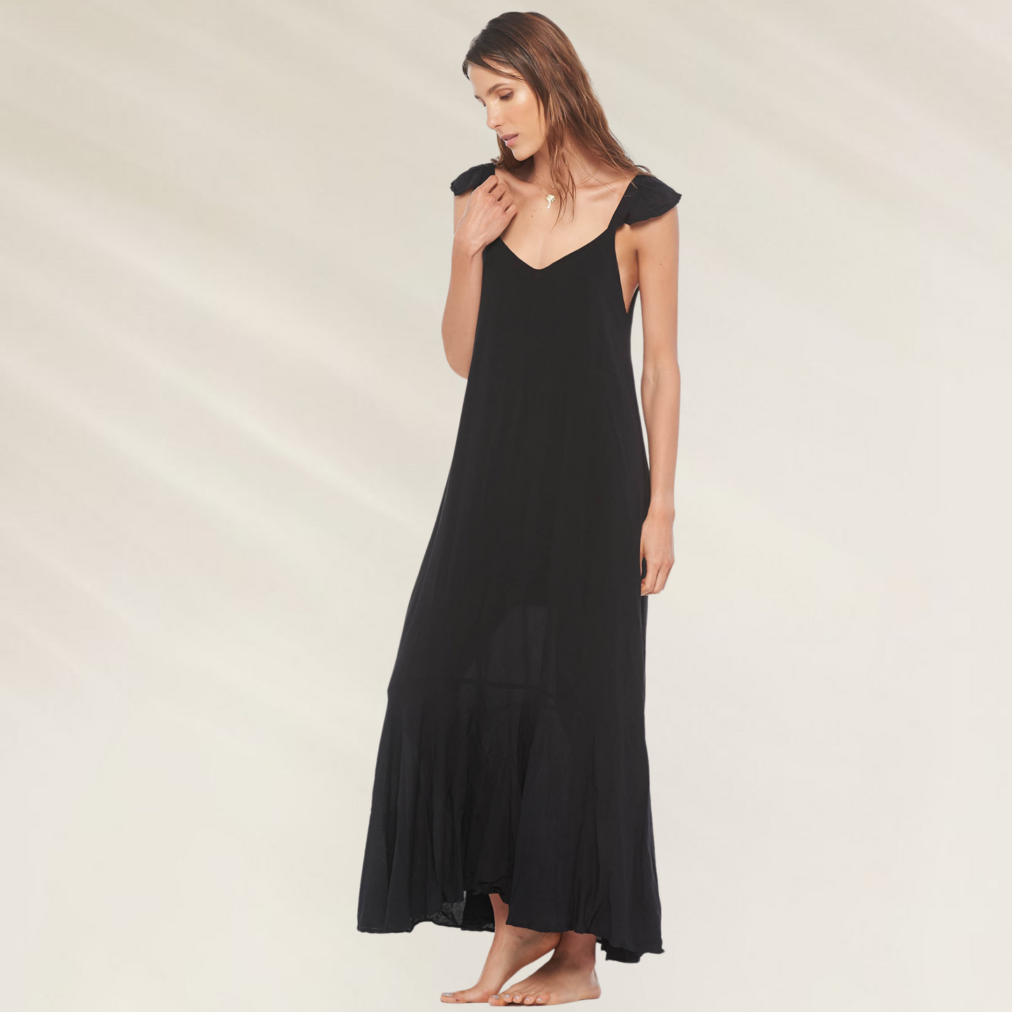 Vestido Preto Longo com Decote em V Malai em tecido leve usado por mulher em fundo claro