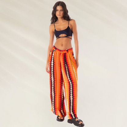Modelo usando Calças Maaji Sabine Hyperflares listradas em tons laranja e vermelho, corte largo e cós com cordão