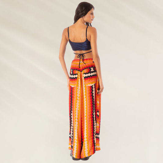 Modelo de costas usando Calças Maaji Sabine Hyperflares estampadas em laranja vermelho e amarelo com cós alto e perna ampla