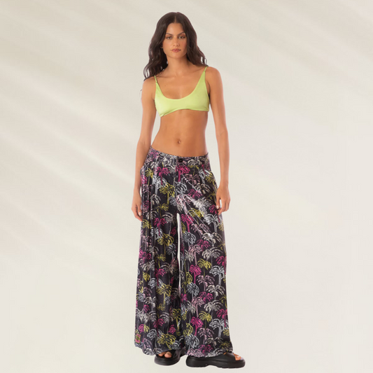 Calças Largas Stella Maaji estampadas com fundo preto usadas por mulher com top verde