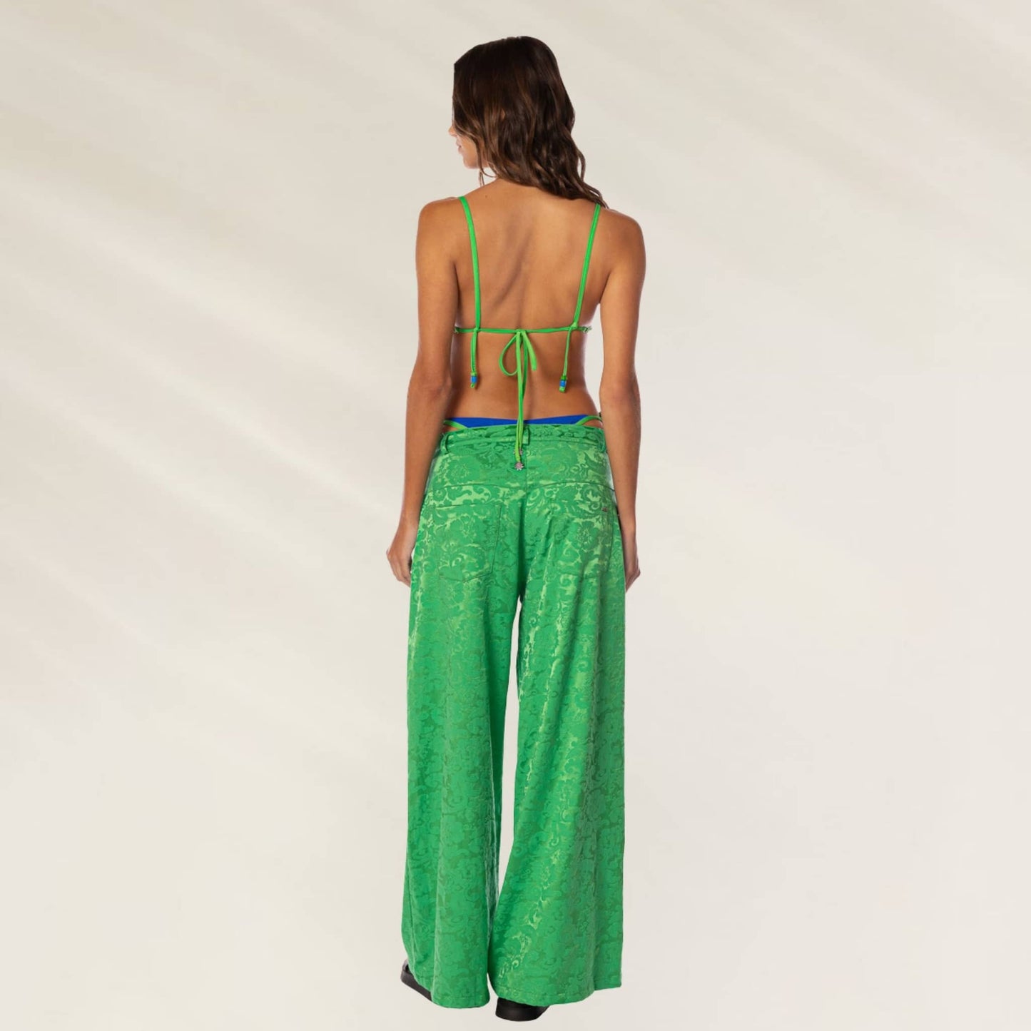 Modelo de calça verde em tecido texturizado, estilo largo da marca Maaji, vista de costas