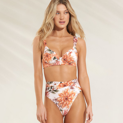 Mulher usando cueca reversível de cintura alta Maaji com estampa floral em tons laranja e branco