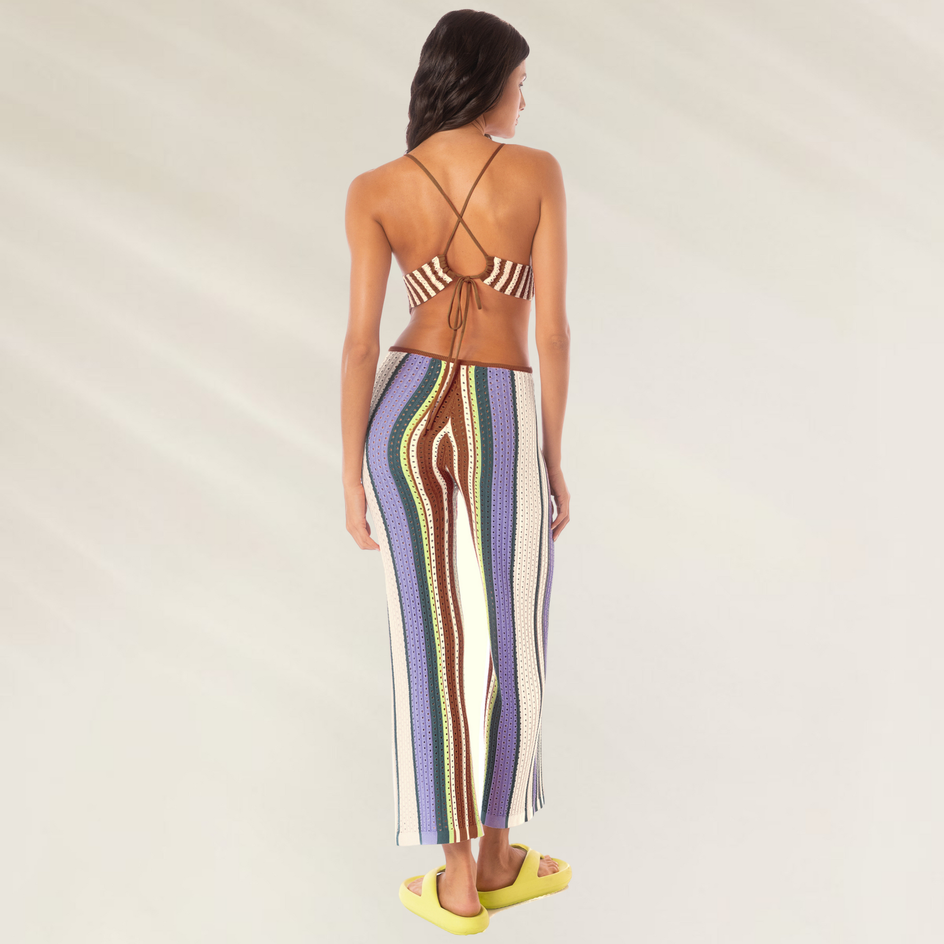 Modelo usando macacao Maaji em crochet Roman Stripe Leave com alças cruzadas e listras coloridas