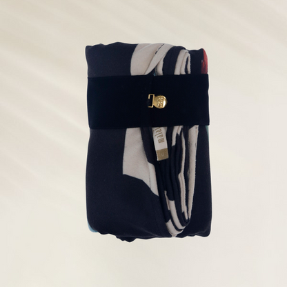 Toalha de Praia Malai – Leveza, Estilo e Praticidade dobrada com suporte preto e detalhe dourado