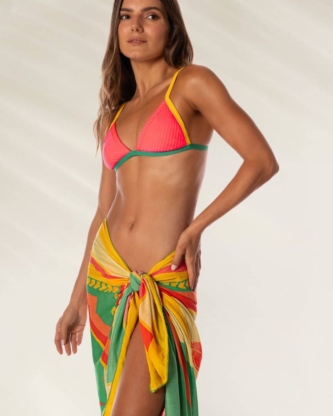 Modelo usando o Pareo Isla Multicolor da Maaji, amarrado na cintura com estampa vibrante