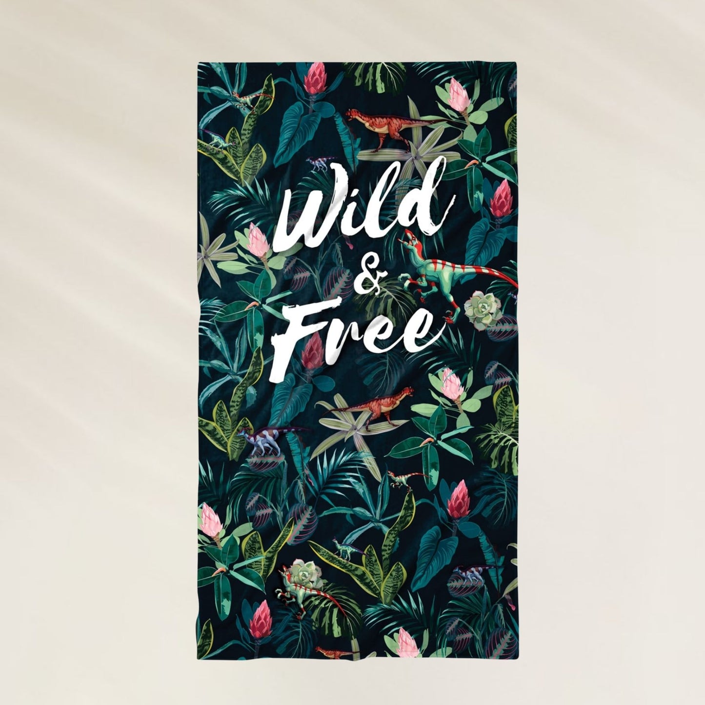 Toalha de Praia Dino com estampa tropical e a frase Wild & Free, ideal para dias de sol
