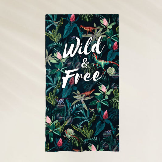 Toalha de Praia Dino com estampa tropical e a frase Wild & Free, ideal para dias de sol