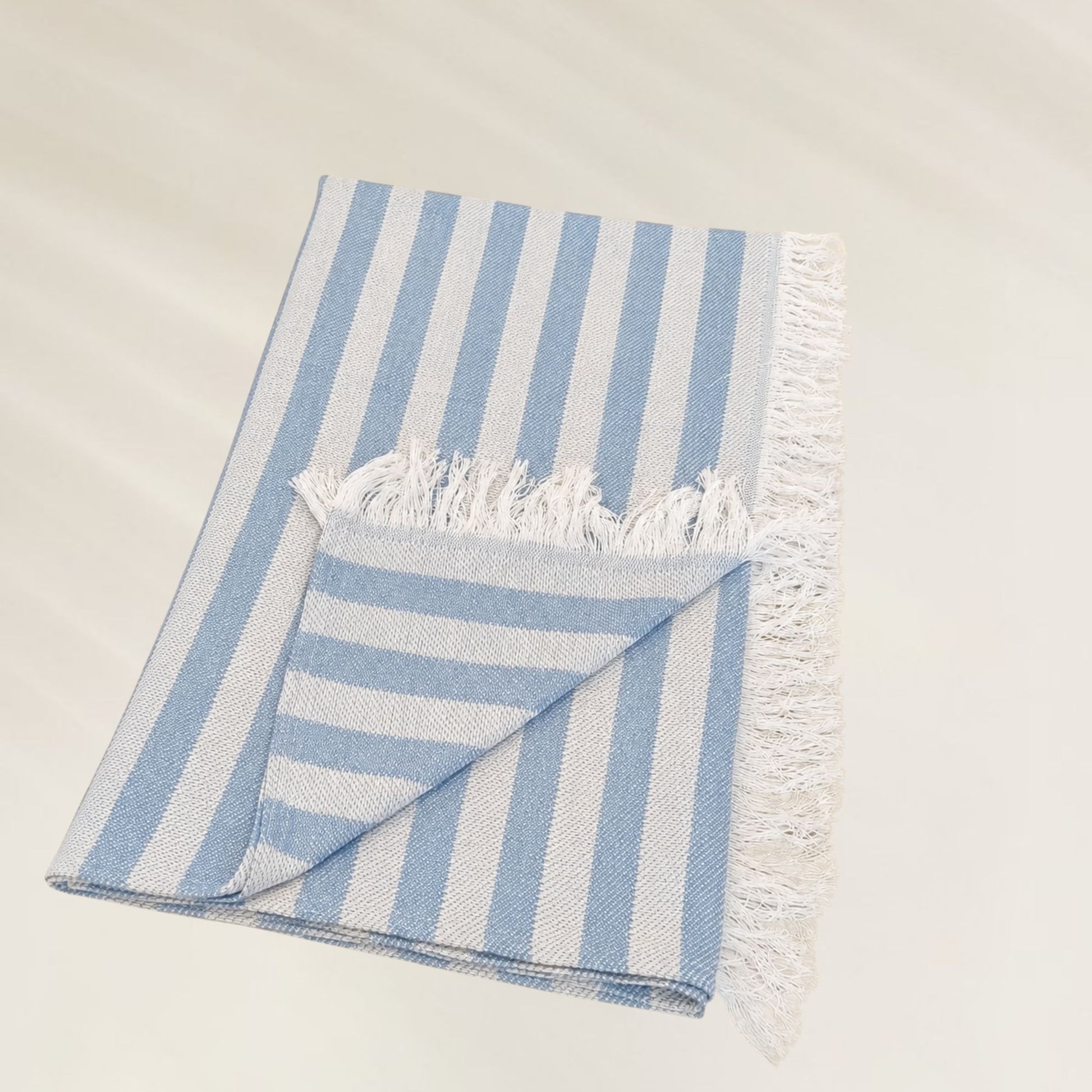 Toalha Ocean Breeze da Kalua em listras azuis e brancas, perfeita para a praia